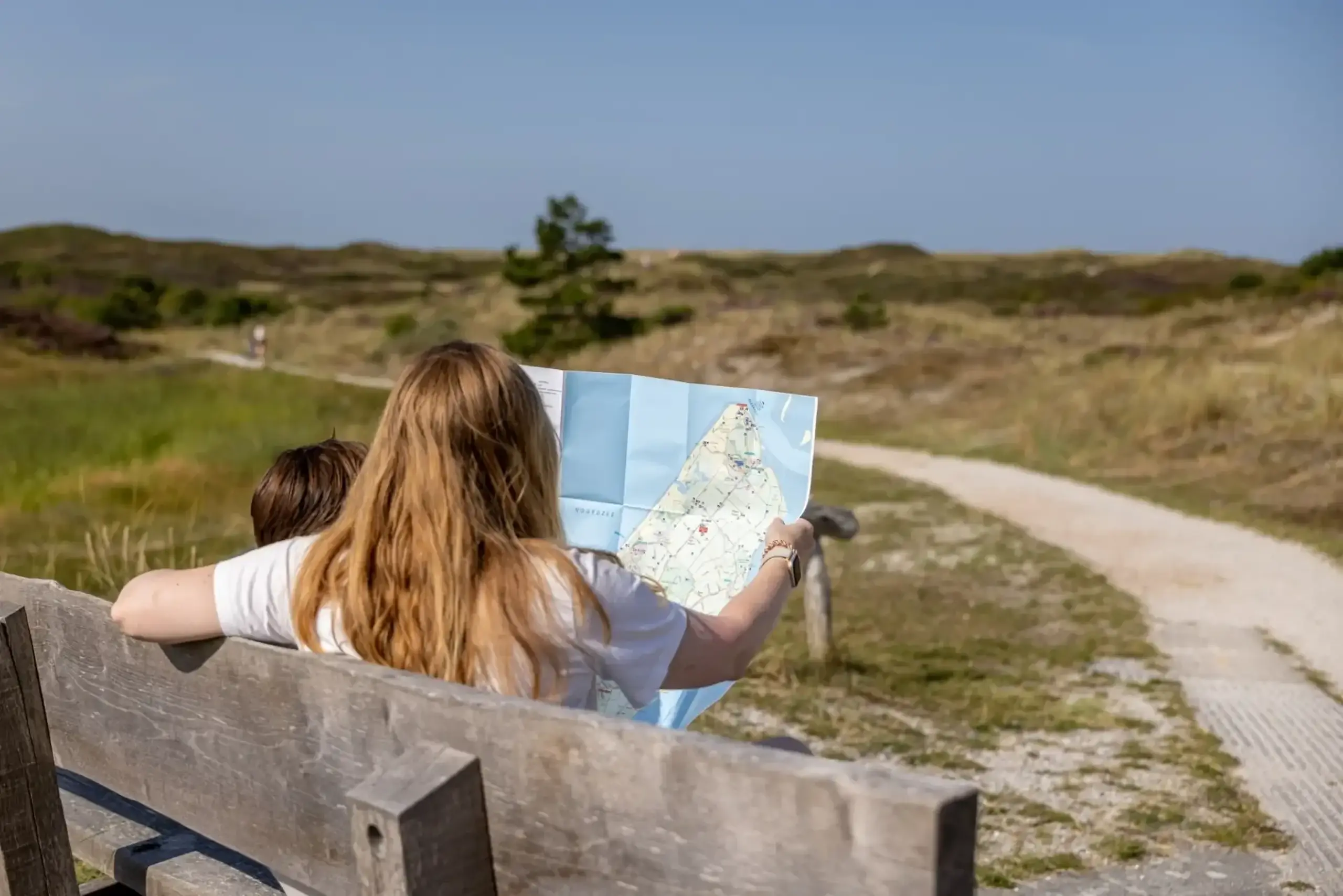 Mother and child are looking at a map in the dunes